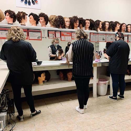 A group of people are standing in a room with mannequin heads.