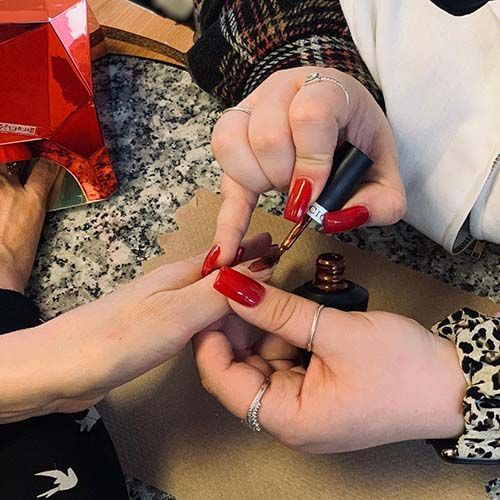 A woman is getting her nails painted by a nail artist.