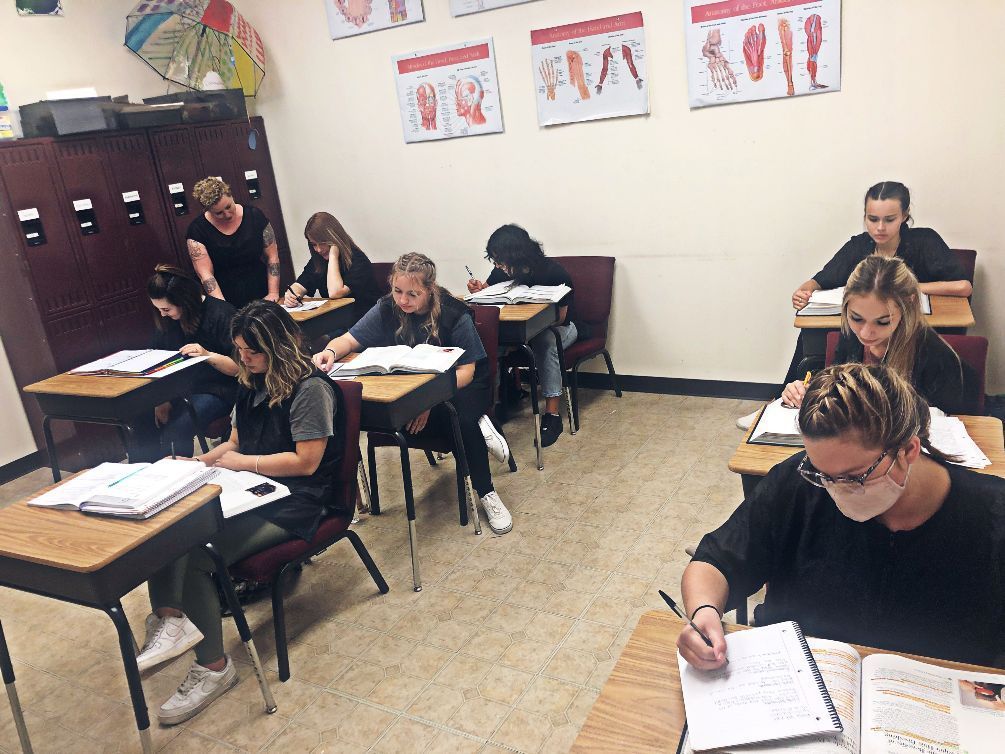 A group of people are sitting at desks in a classroom.
