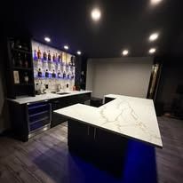 Modern bar with marble tables, backlit shelves of bottles, and dark ceiling lights