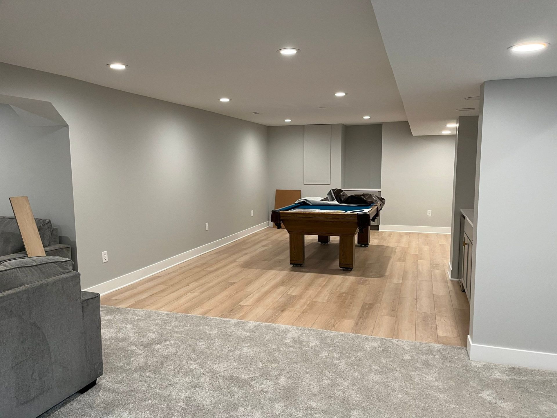 Spacious basement rec room with pool table, gray walls, recessed lights, and light wood flooring