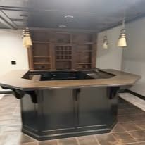 Basement bar with dark wood counter, built-in shelving, and pendant lights over tiled floor