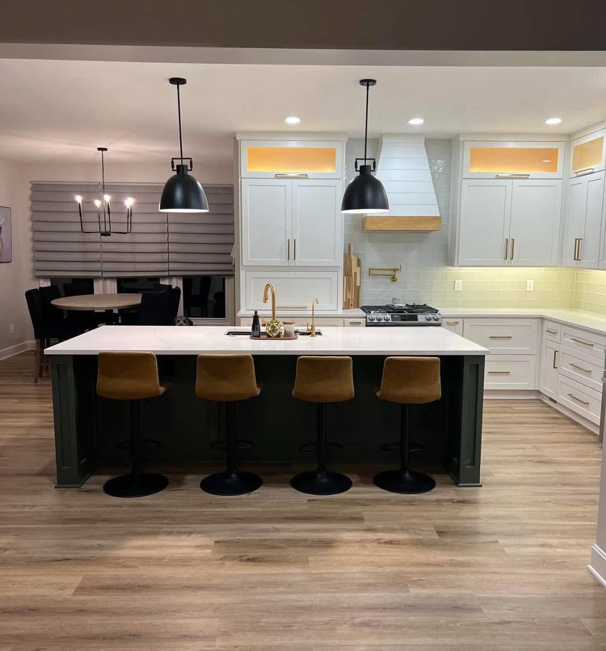 Modern kitchen with white cabinets, island seating, black pendant lights, and light wood flooring