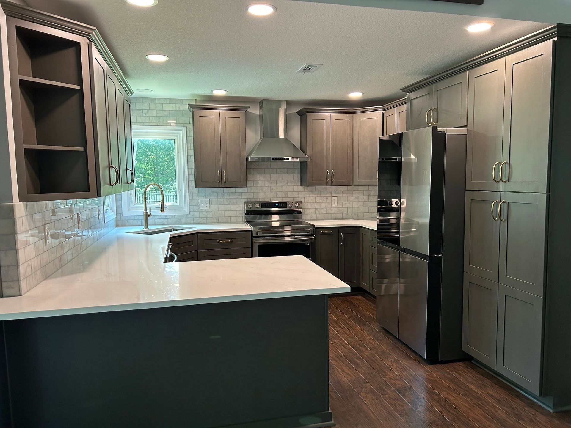 Modern kitchen with gray cabinets, white countertops, stainless steel appliances, and wood flooring