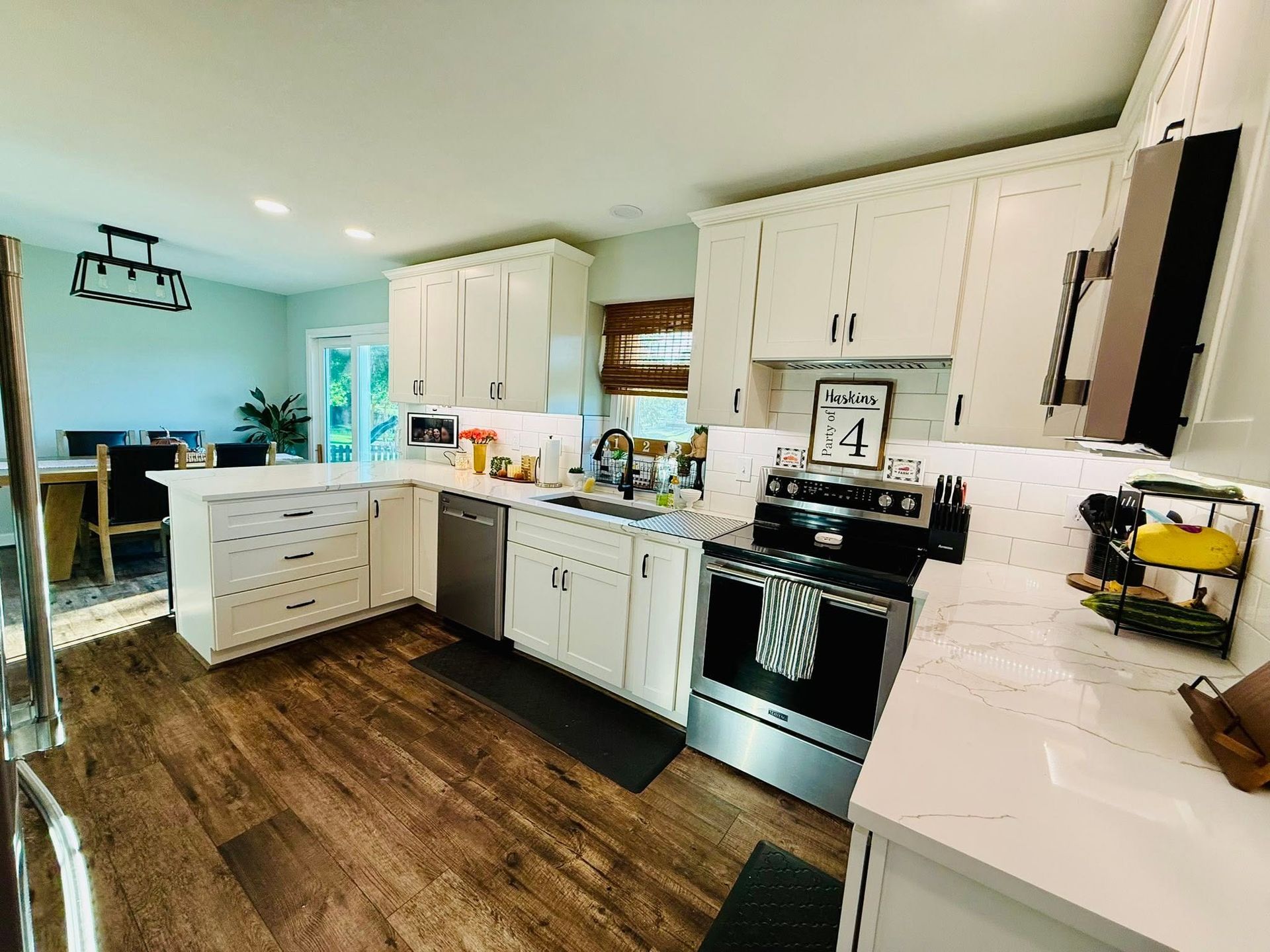 Bright kitchen with white cabinets, black stove, and wood floors, viewed from the doorway.