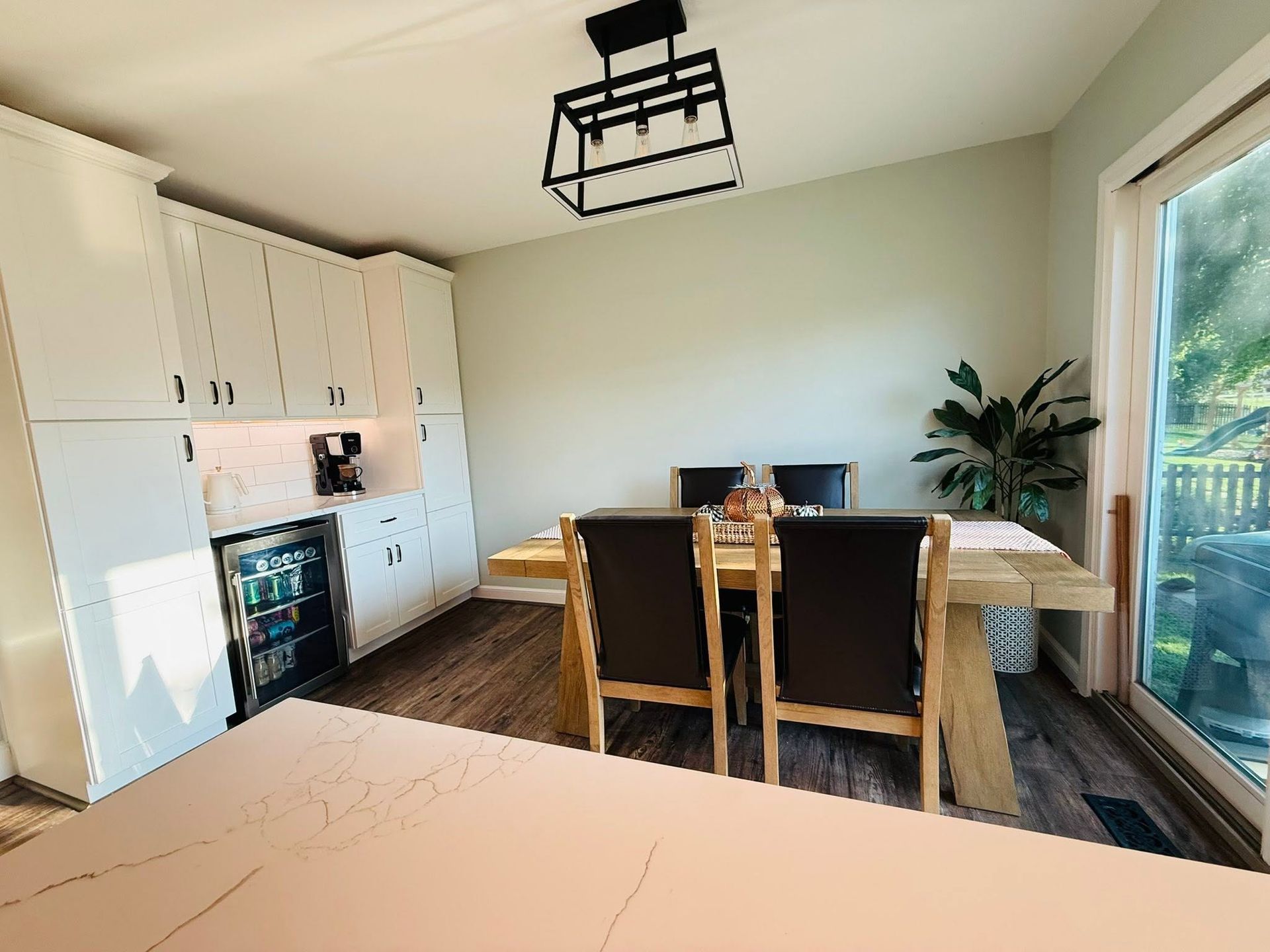 Bright dining room with wooden table and chairs, white cabinets, and a large sliding glass door.