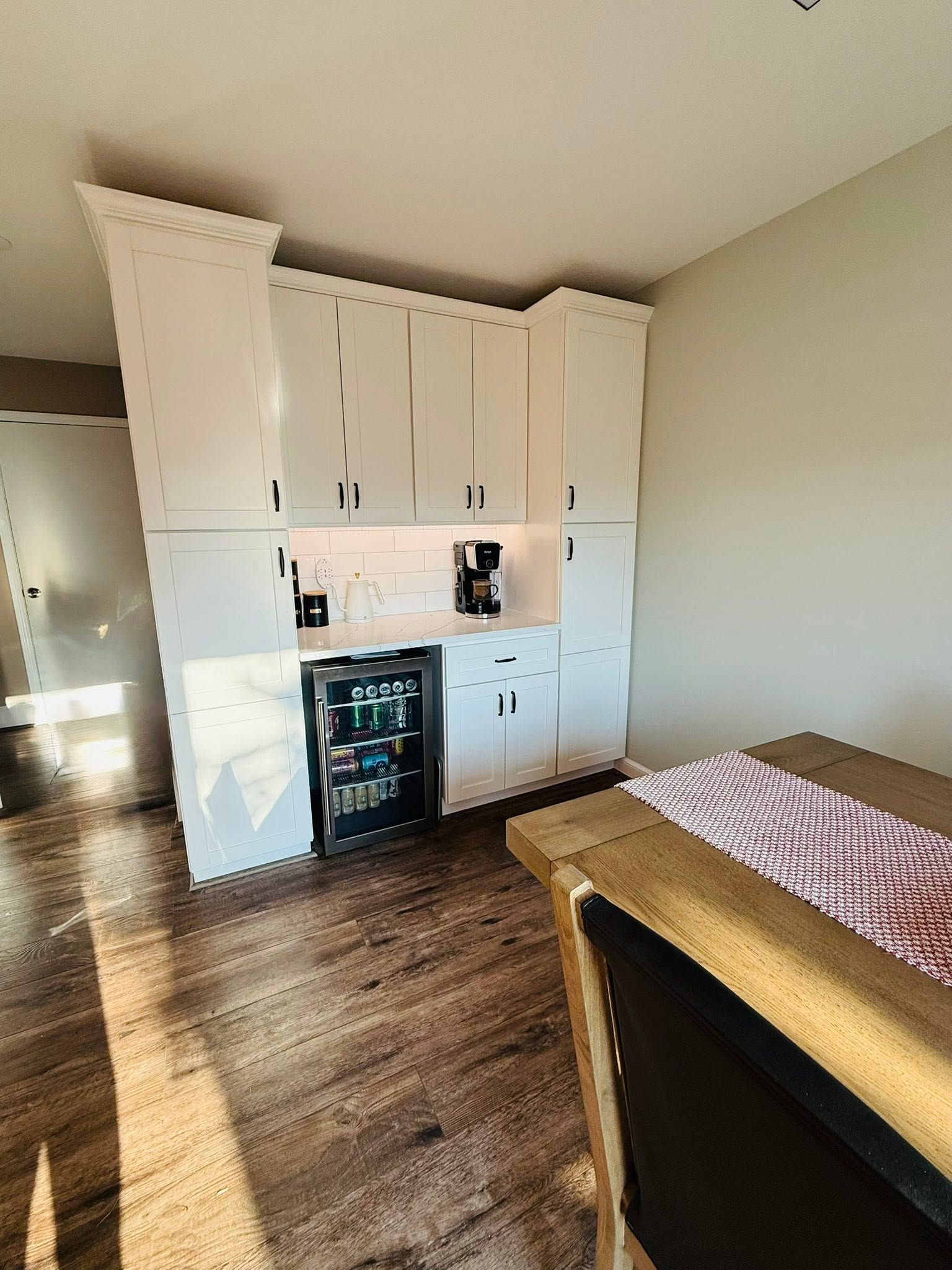 Small bedroom with white built-in cabinets, a mini fridge, wood floor, and a bed in the foreground.