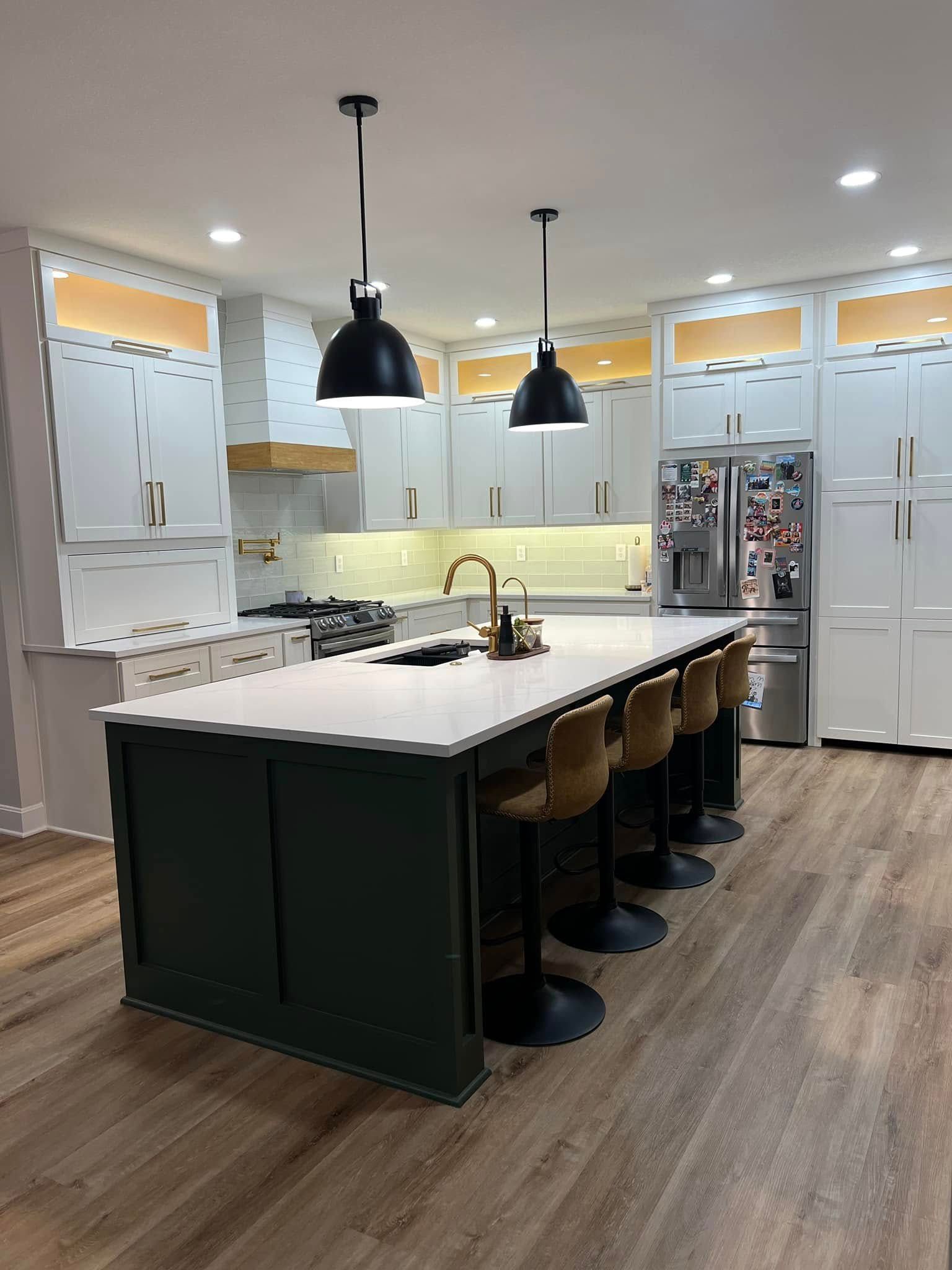 Modern kitchen with white cabinets, large island, pendant lights, and bar stools on wood flooring