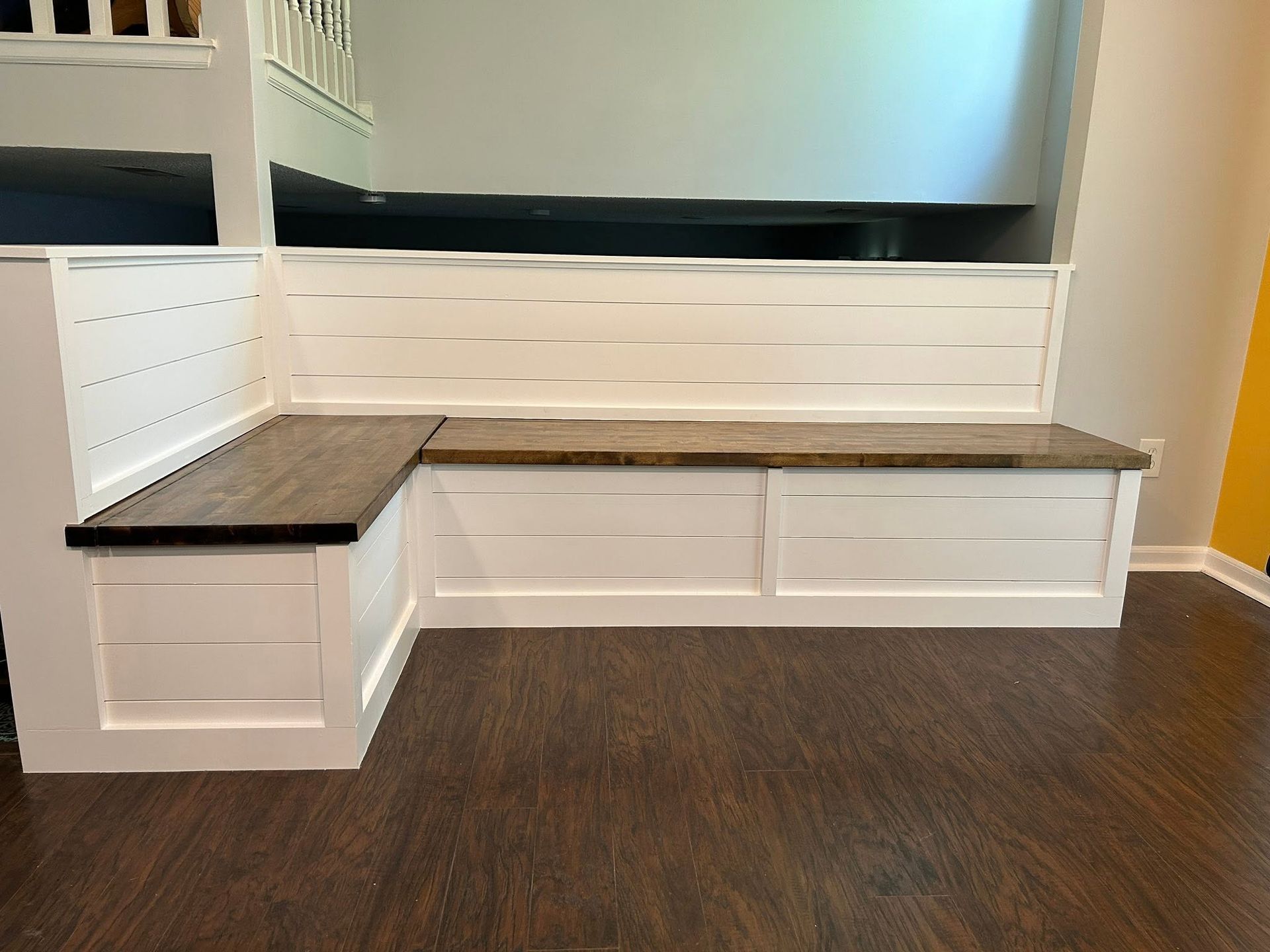 White built-in mudroom bench with drawers and black countertops against a wall in a hallway