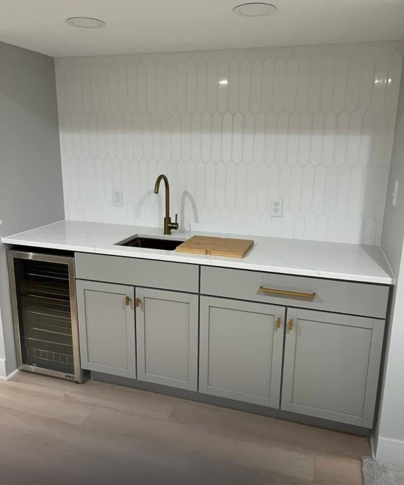 Modern kitchen with white cabinets, black sink, gold faucet, and built-in wine cooler