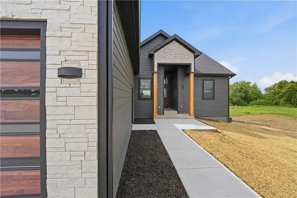 Modern gray house exterior with front entry, concrete walkway, and gravel landscaping