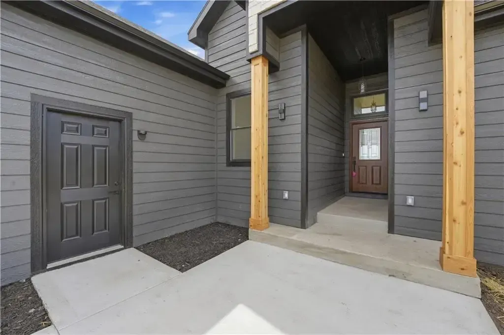 Modern house entryway with gray siding, wooden posts, and a concrete front porch