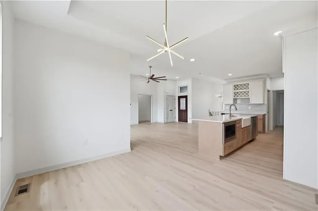 Bright open-plan kitchen and living area with white walls, light wood floors, and a kitchen island