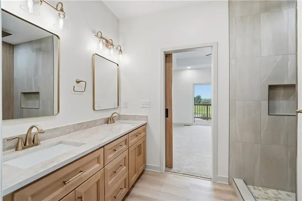 Bright bathroom with double vanity, large mirror, and tiled walk-in shower.