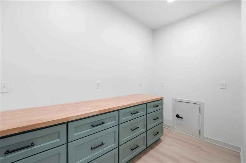 Empty built-in desk with mint drawers and wood countertop in a white room