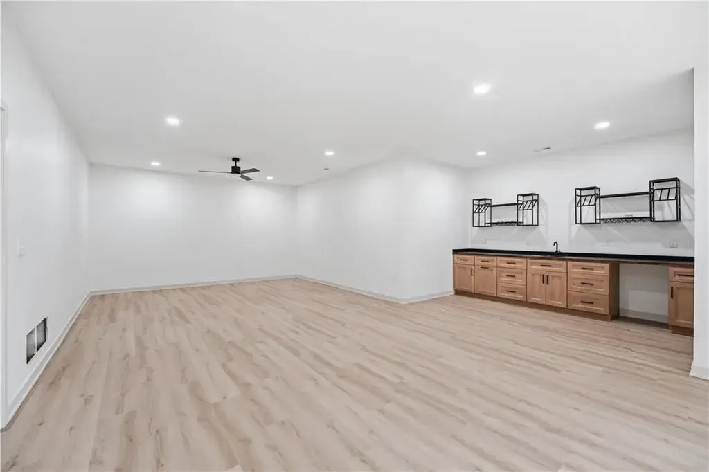 Spacious white living room with light wood floors and a wood cabinet along one wall