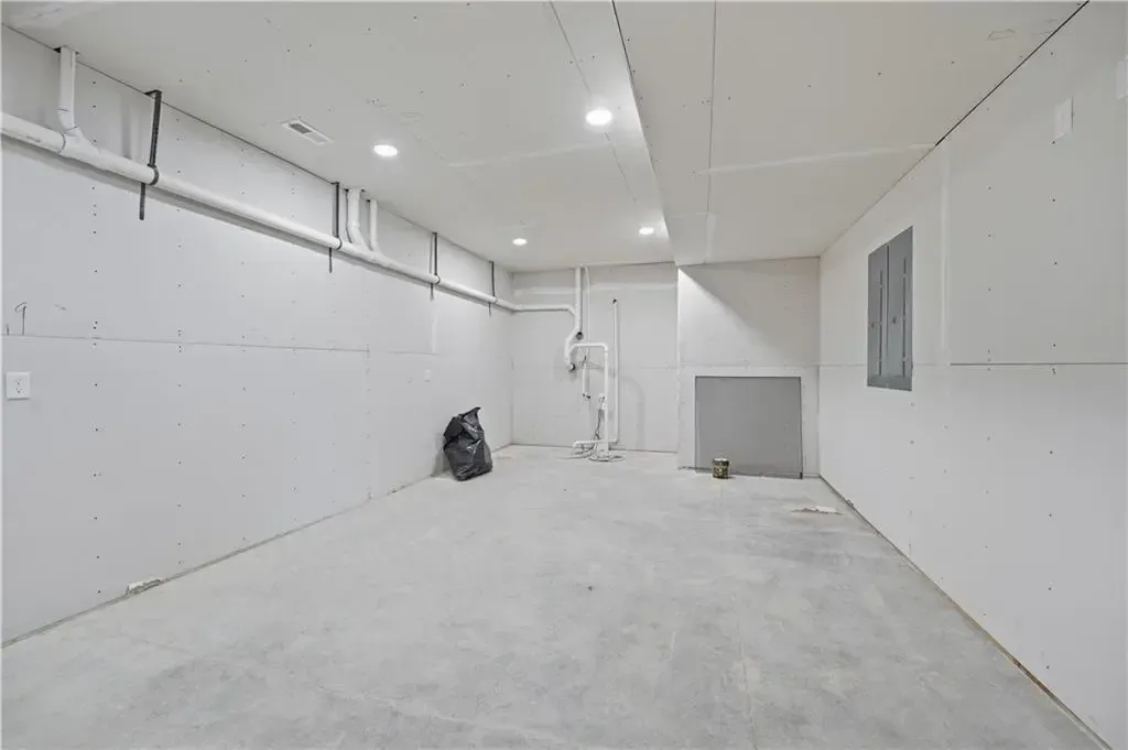 Empty white industrial room with concrete floor, overhead lights, and a worker standing near the back wall