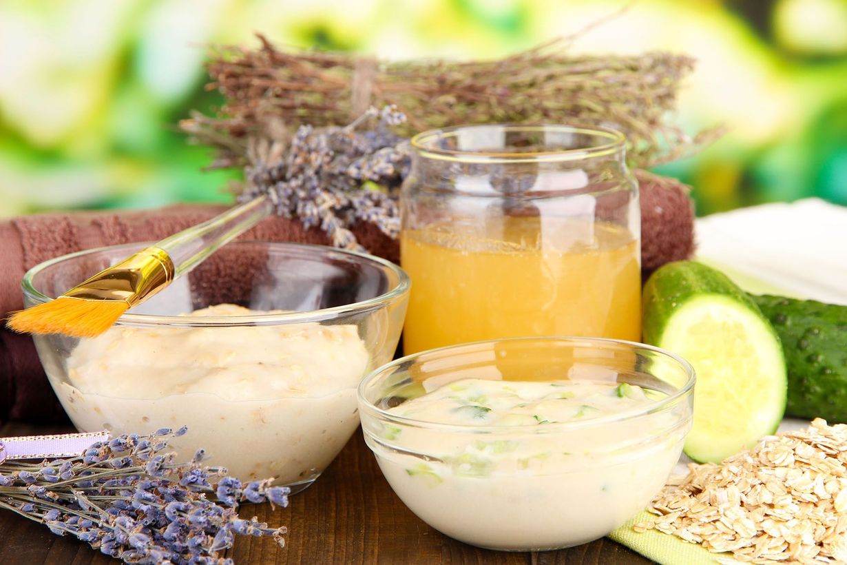 Herbal beauty products with cream, oil, lavender, lime slices, and oats on a bright table.