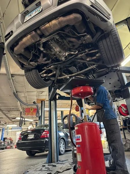 A mechanic works under a car raised on a hydraulic lift in an auto repair shop.