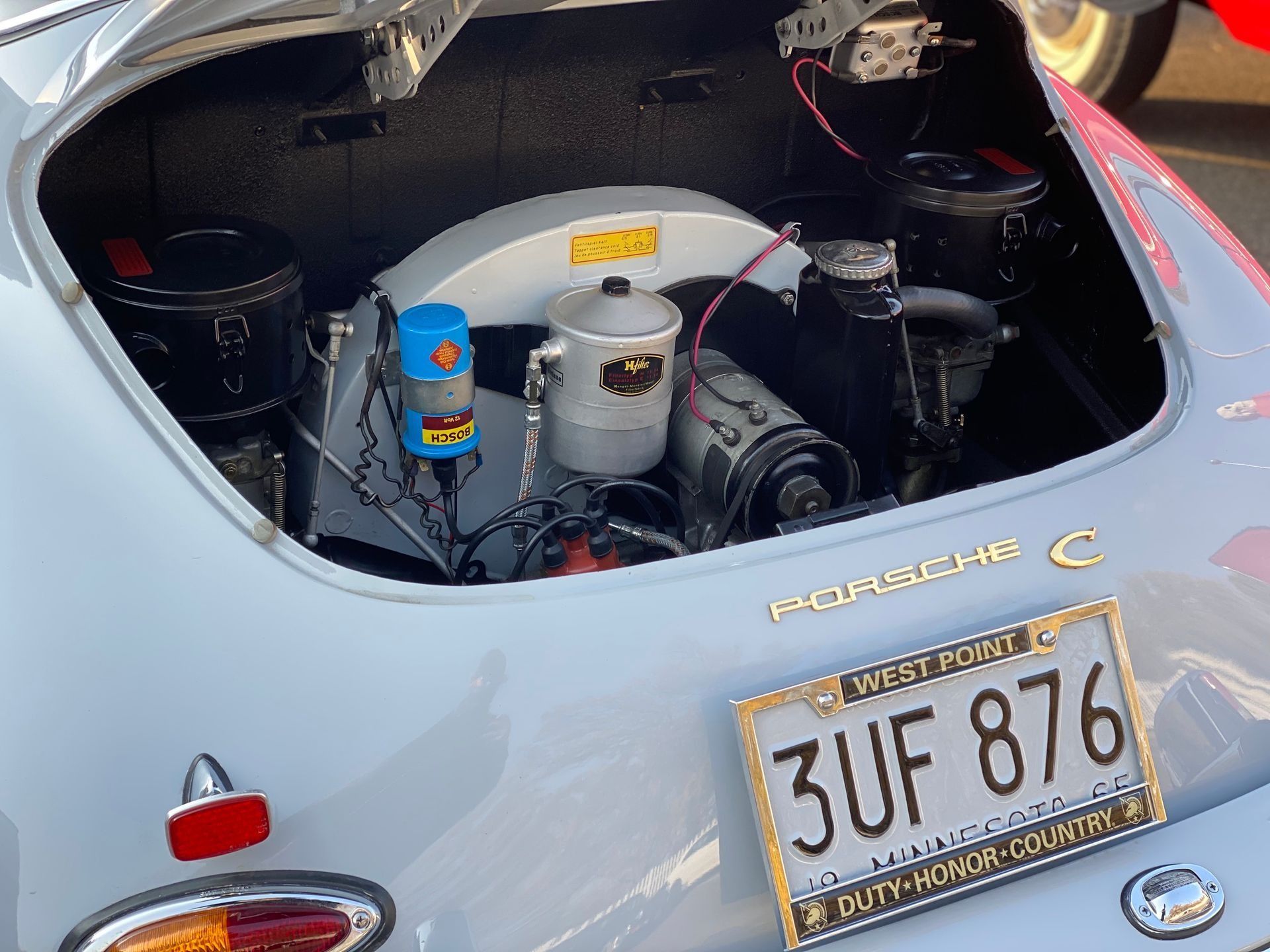 The open engine compartment of a classic light blue Porsche 356 C with a West Point license plate 3UF 876.
