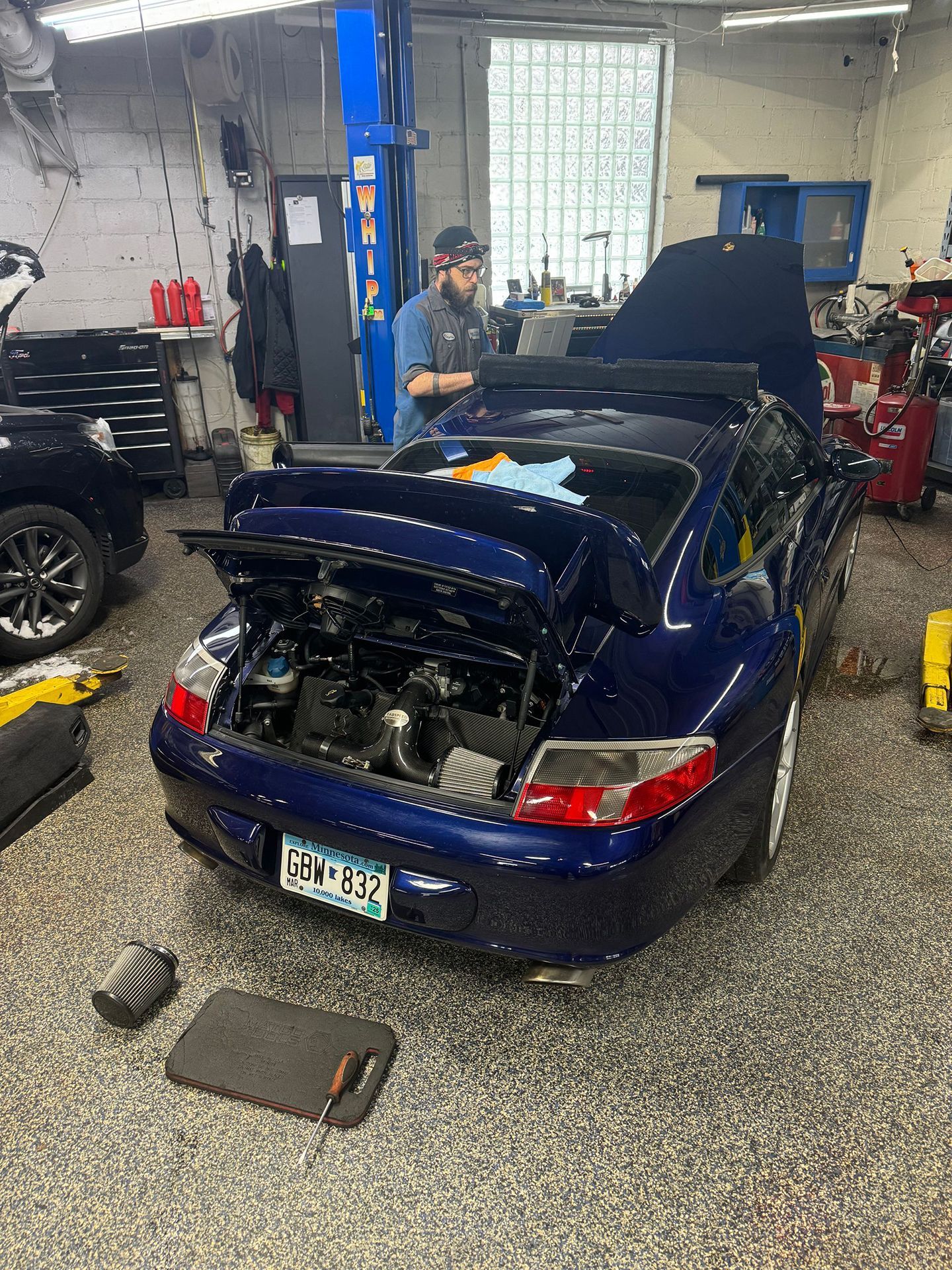 Blue sports car in a mechanic’s garage with its rear body panels removed during repairs