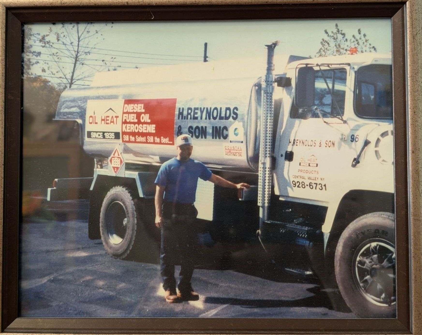 A man is standing in front of a mreynolds truck
