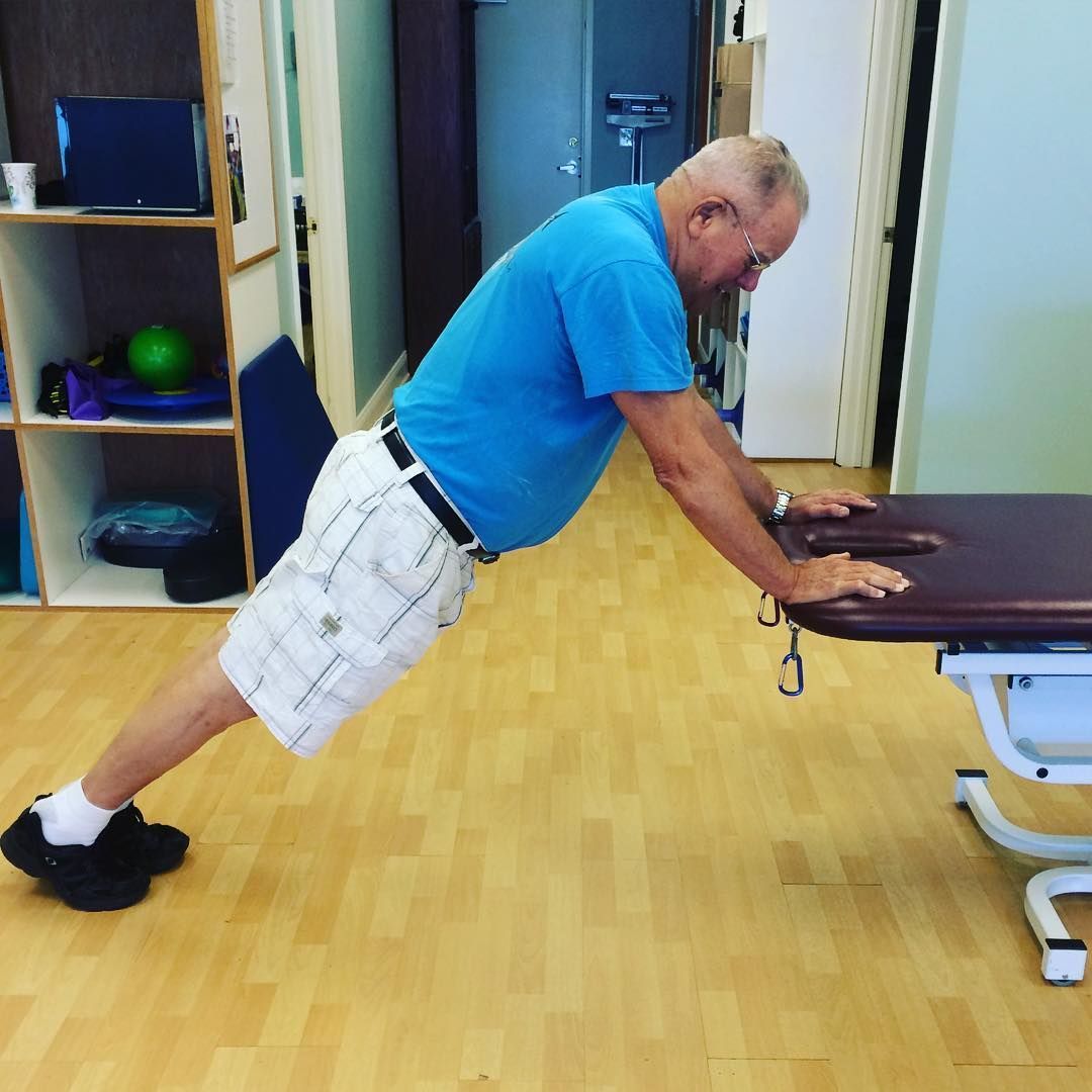 A man in a blue shirt is doing push ups on a table