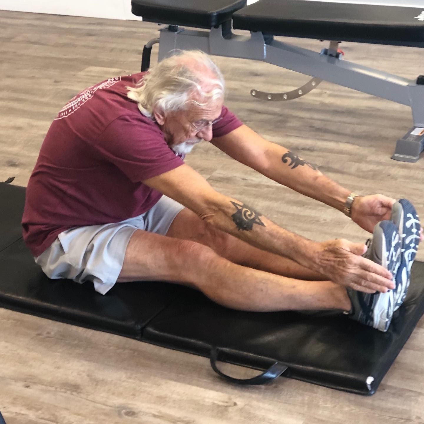 A man is sitting on a mat stretching his legs