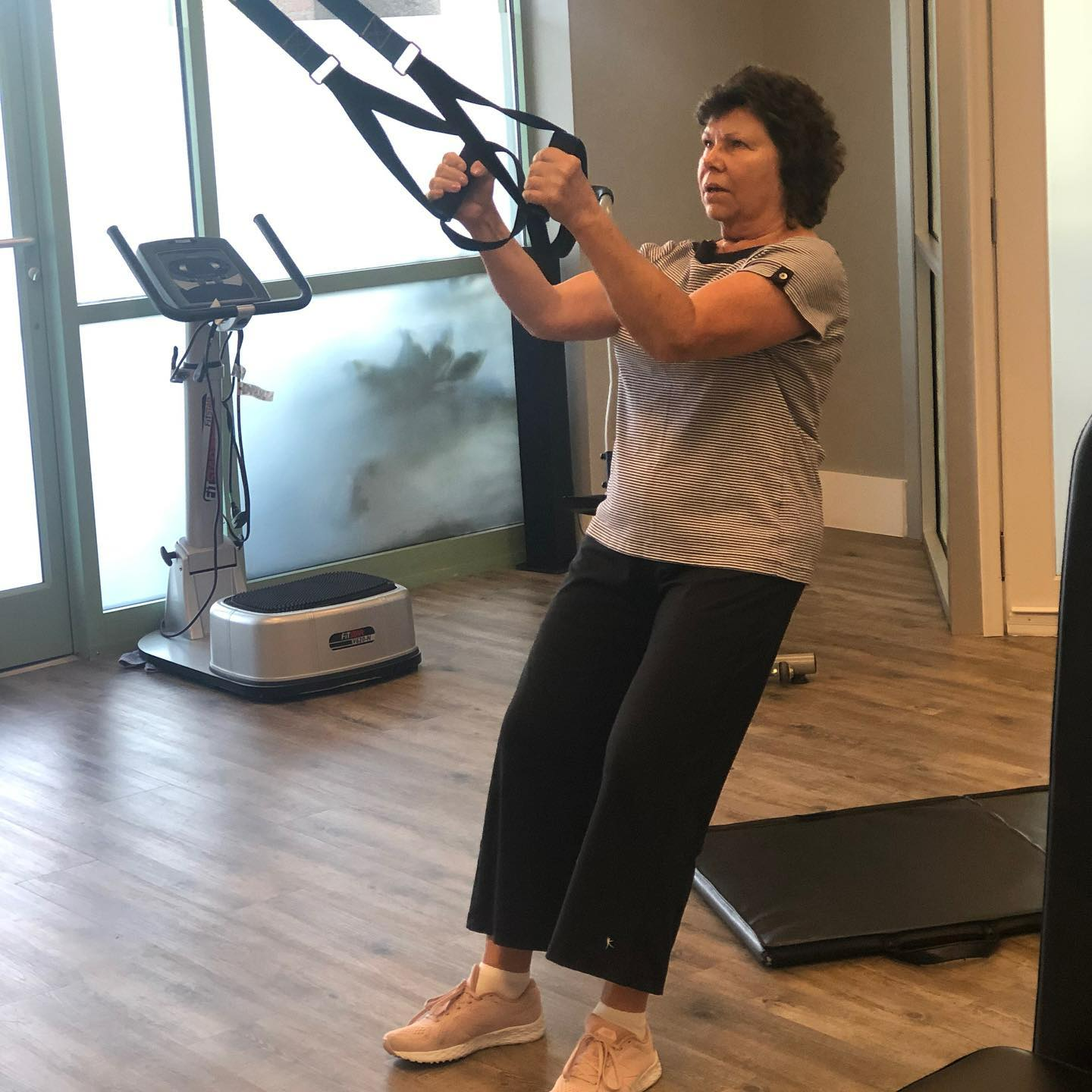 A woman is using a trx machine in a gym.