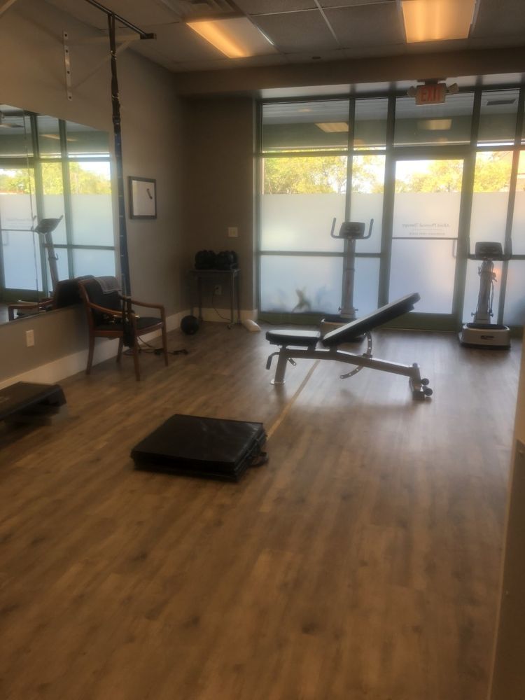 A gym with a bench , treadmill , and mirror.