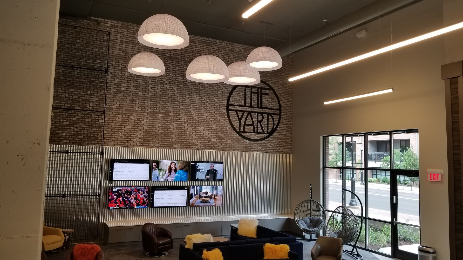 A living room with a lot of furniture and televisions on the wall.