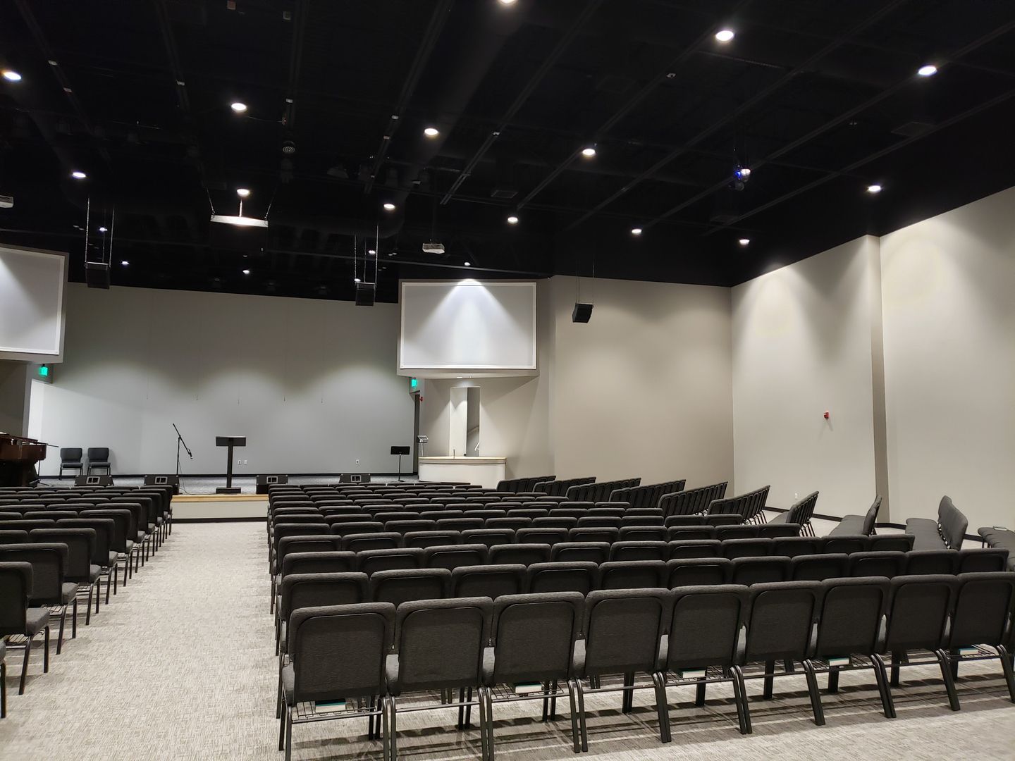 An empty auditorium with rows of chairs and a projector screen