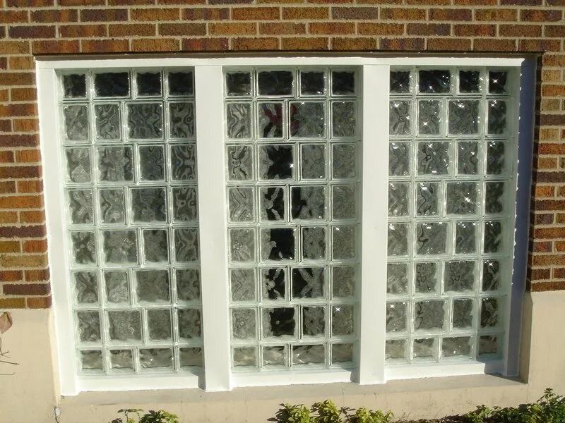 Glass block window set in a white frame against a brown brick building exterior.