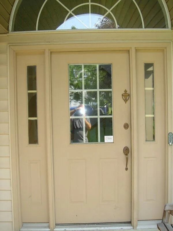 Beige front door with glass window and side panels, beneath a semi-circular window.