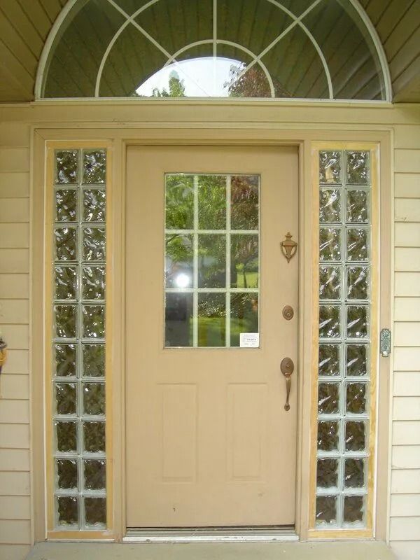Tan front door with sidelights and an arched transom, cream-colored exterior.