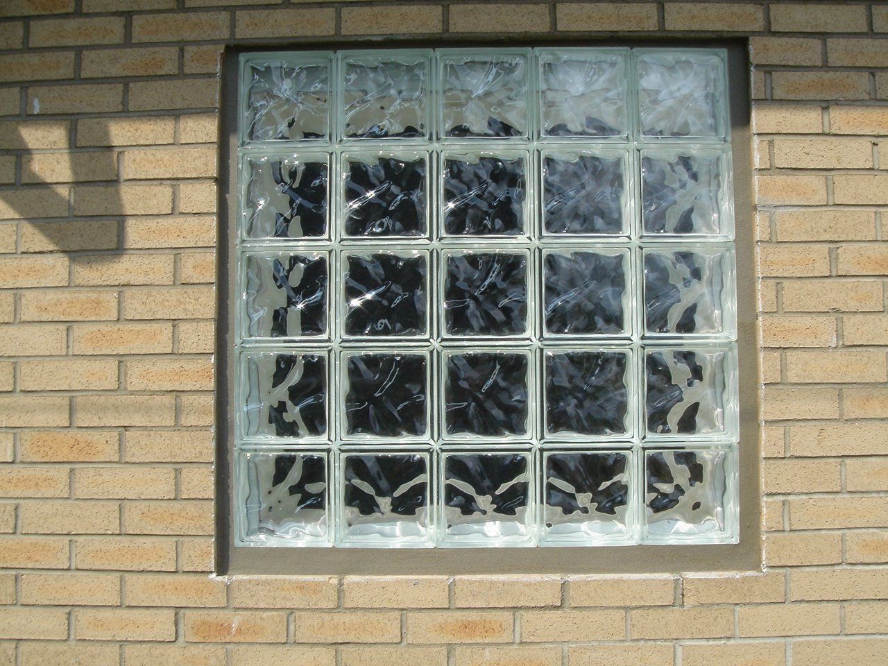 Glass block window set in a beige brick wall.