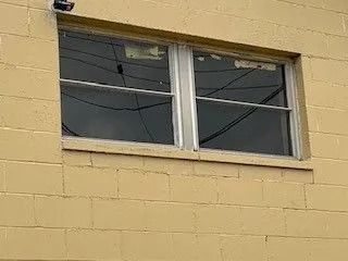 Window on a yellow brick wall with power lines visible through the glass.