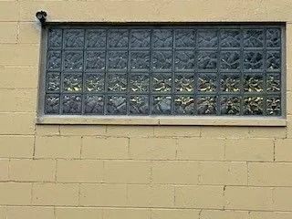Window made of glass blocks in a yellow brick wall.