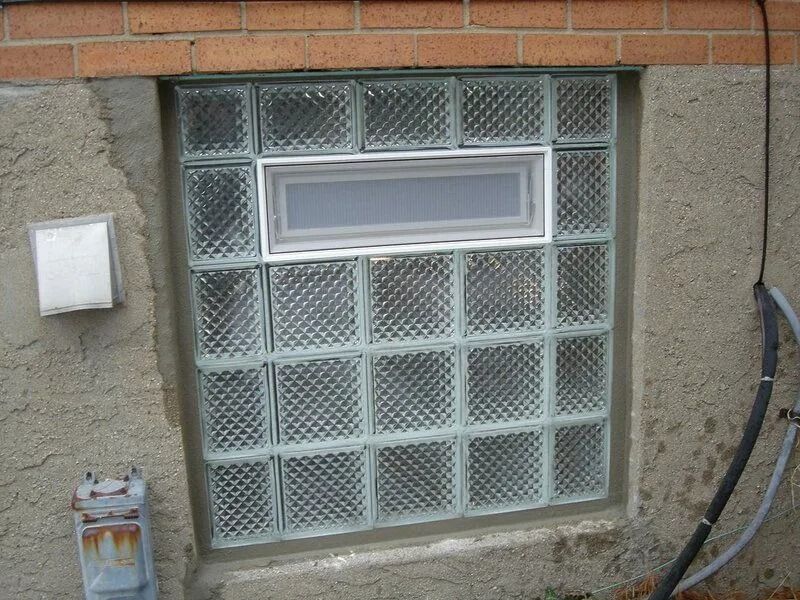 Glass block window with a small window in the center, set in a stucco wall.