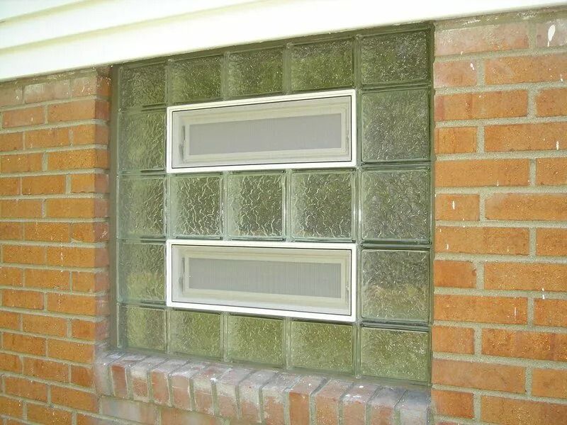 Glass block window in a brick wall with two rectangular vent windows.