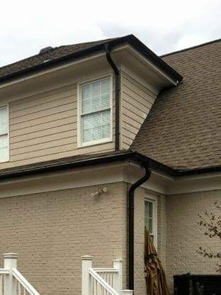Beige house with dark gutters, windows, and a brown roof.