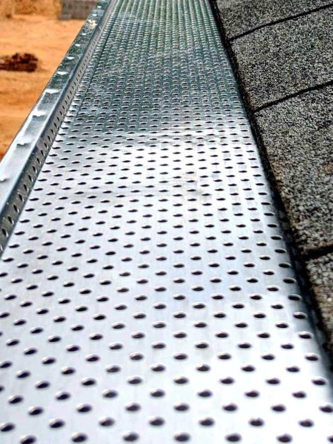 Perforated metal gutter guard on a house roof, protecting the gutter from debris.
