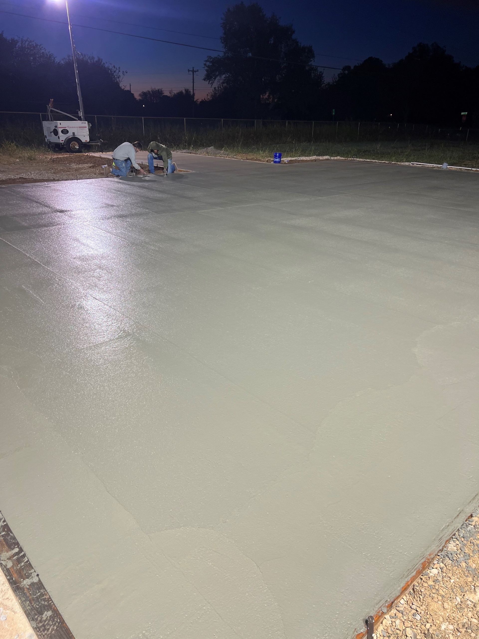 A group of people are working on a concrete floor at night.