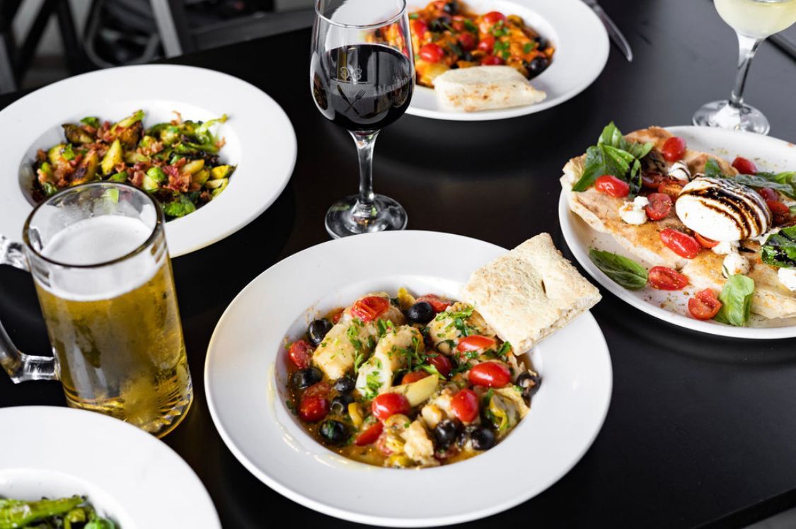 A table topped with plates of food and glasses of wine.