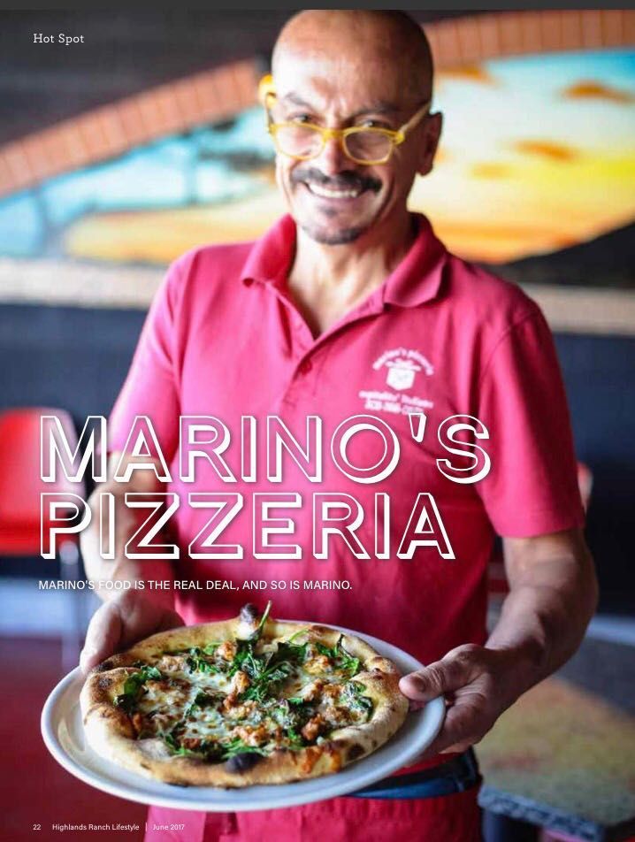 A man in a red shirt is holding a pizza in front of a sign that says Marino's Pizzeria.