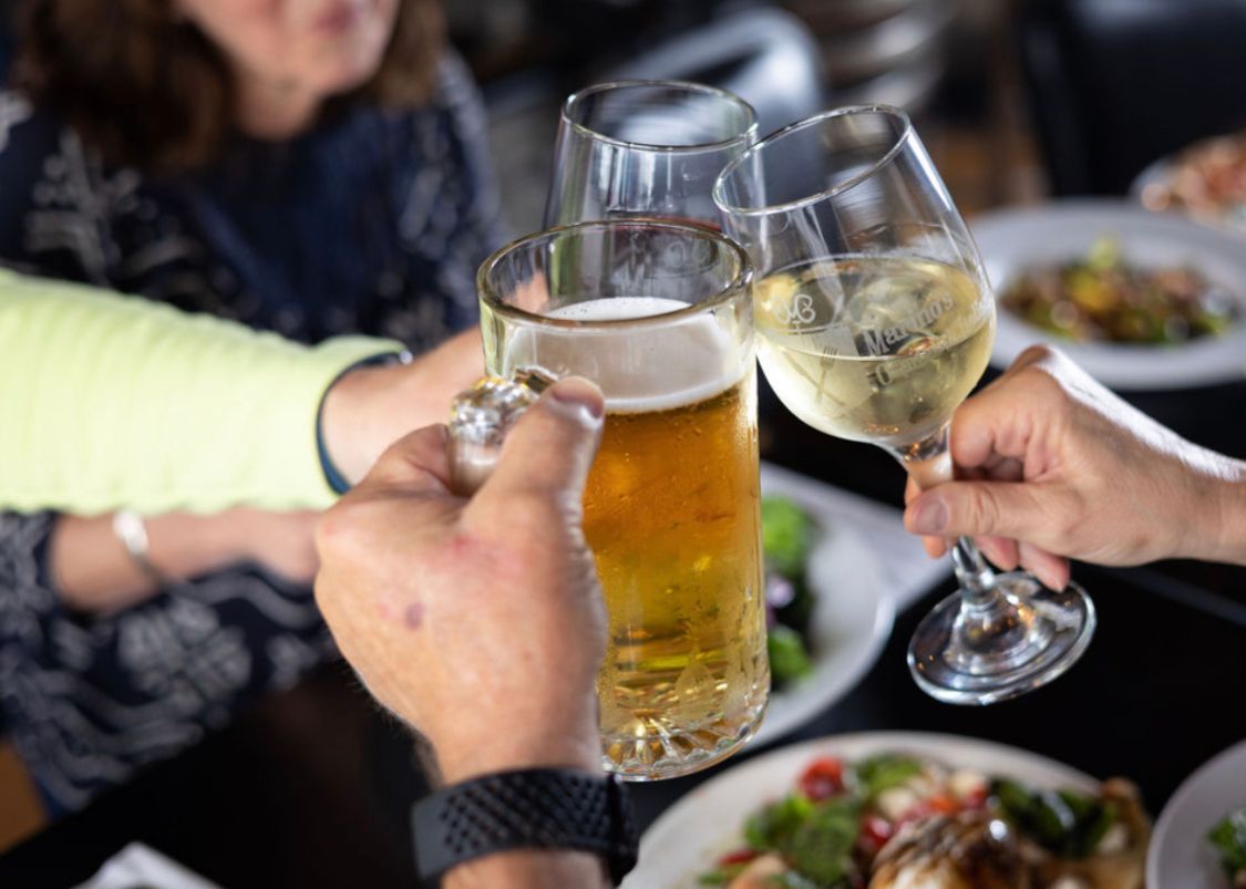 A group of people are toasting with beer and wine glasses.