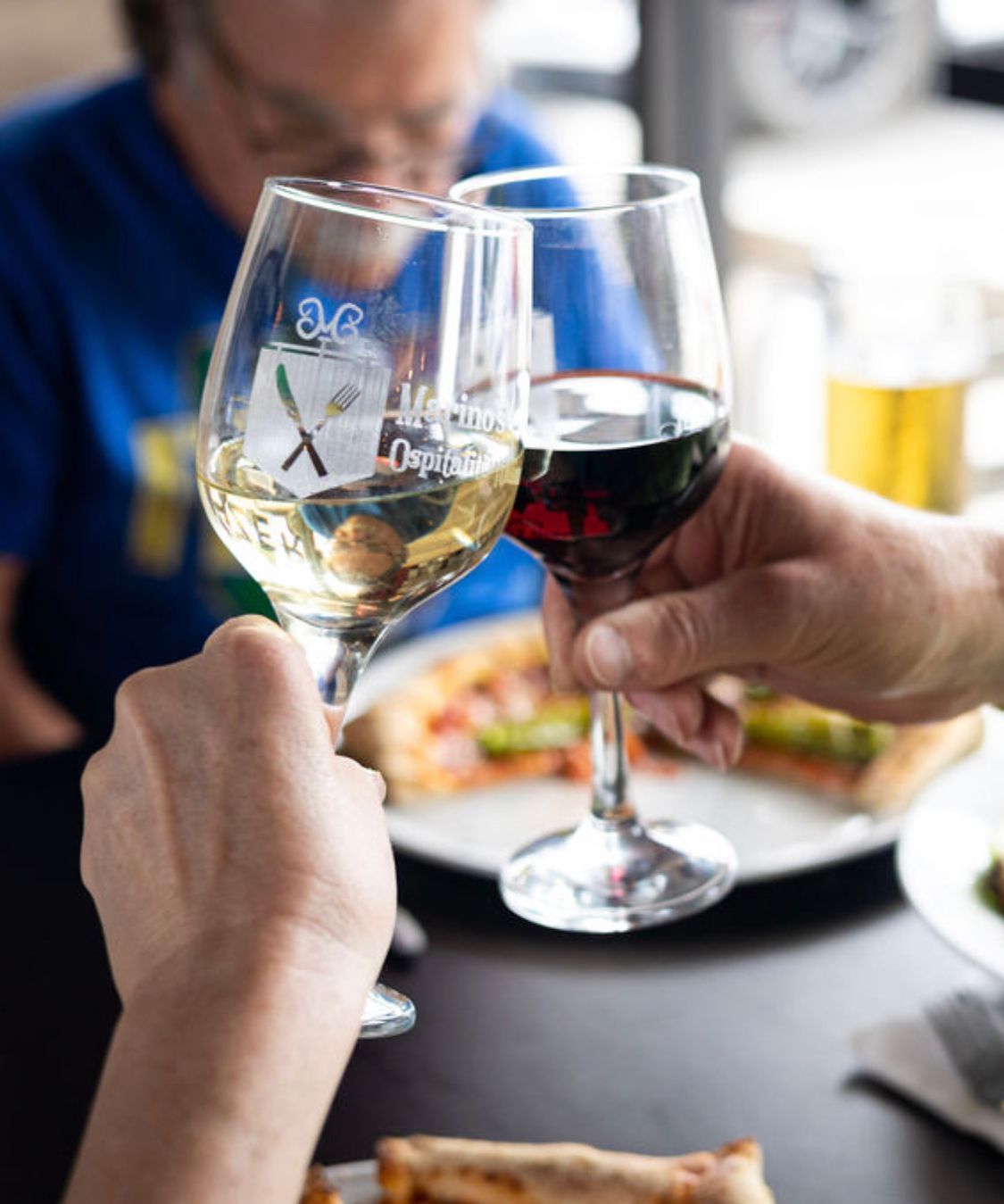 Two people are toasting with wine glasses at a table.