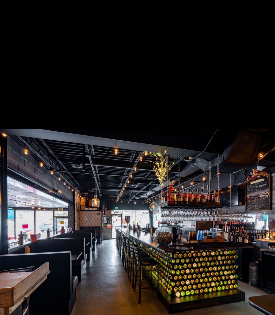 A restaurant with a long bar and a lot of bottles on the counter.