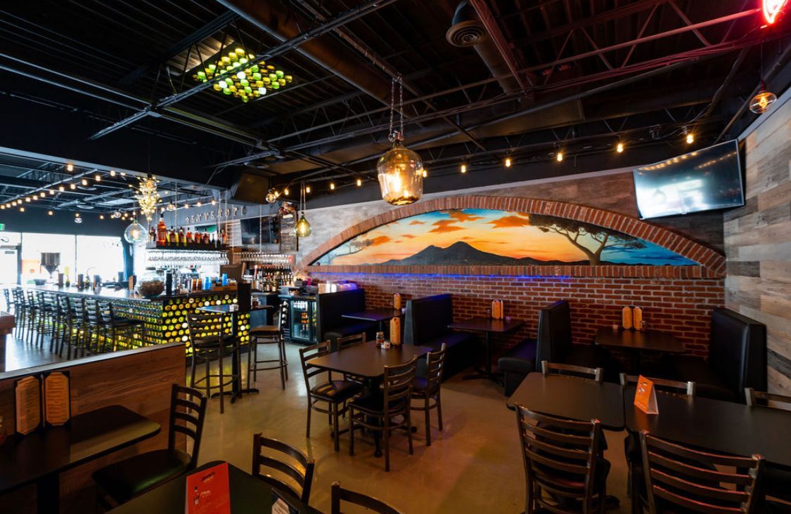 A restaurant with tables and chairs and a painting on the wall.