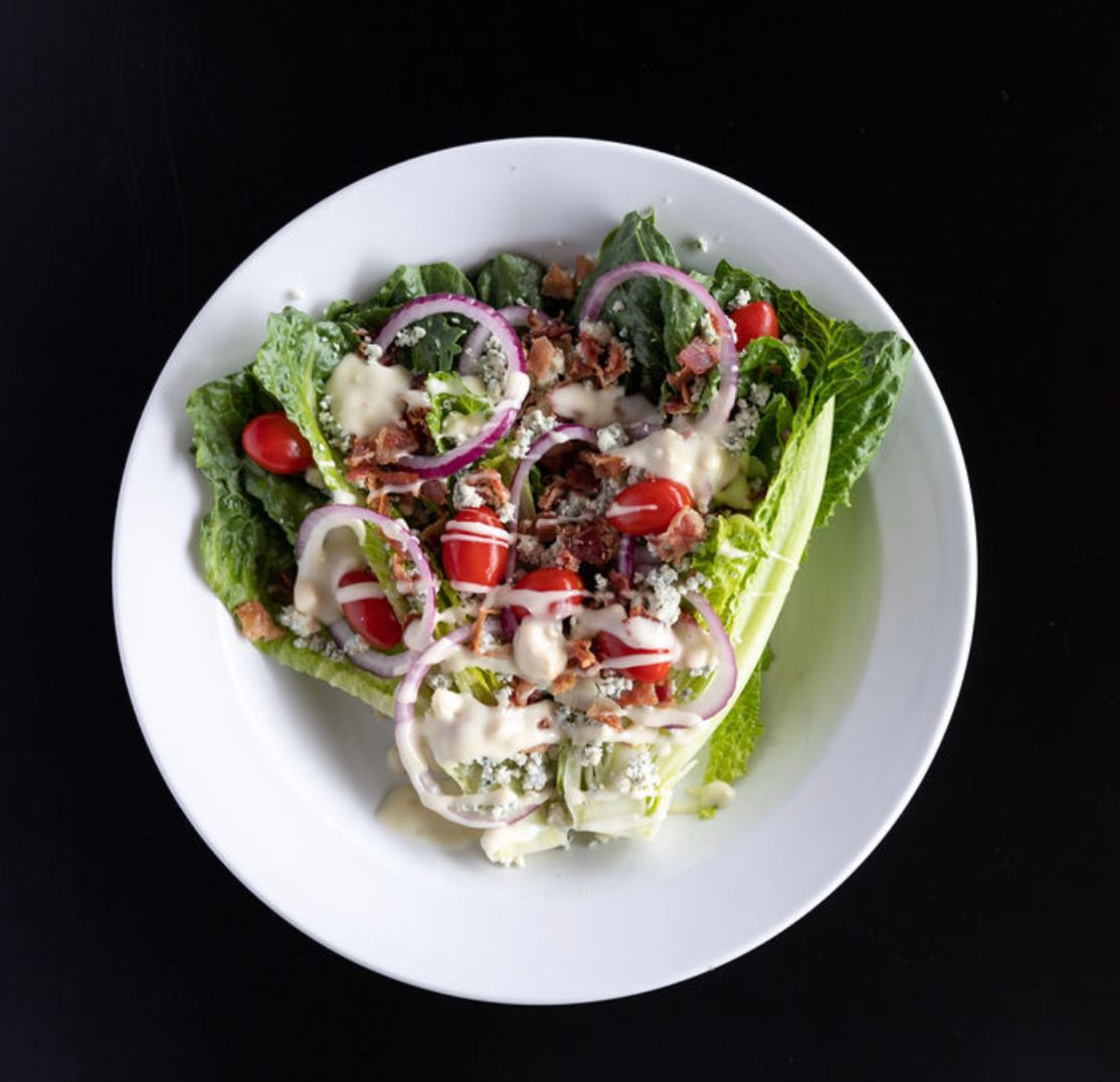 A white plate topped with a salad of lettuce, tomatoes, and onions.